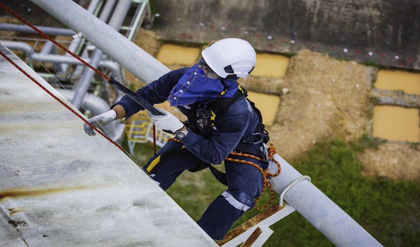 roofer fully harnessed inspecting the edge of a roof