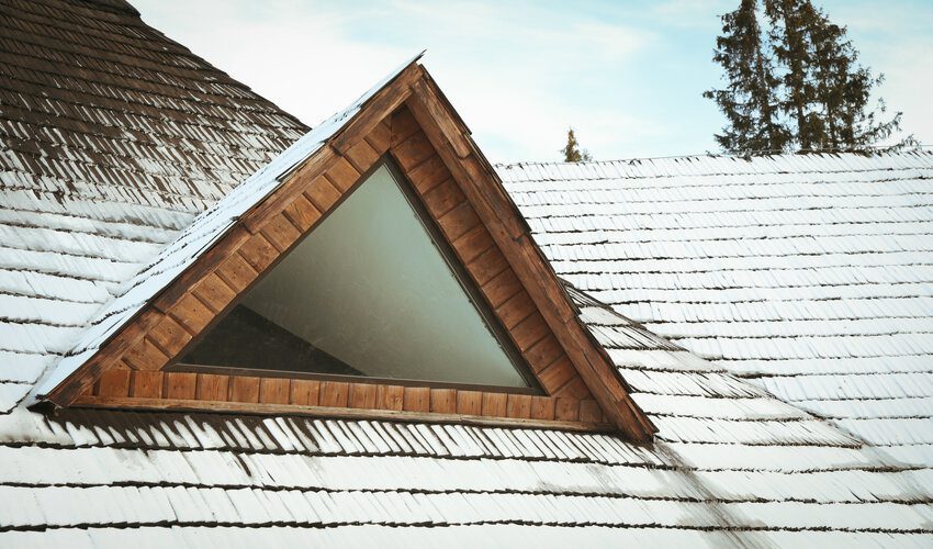 slopped wooden roof with snow on it's lower shingles