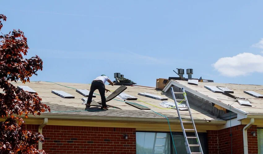 roofer on a roof moving shingles around