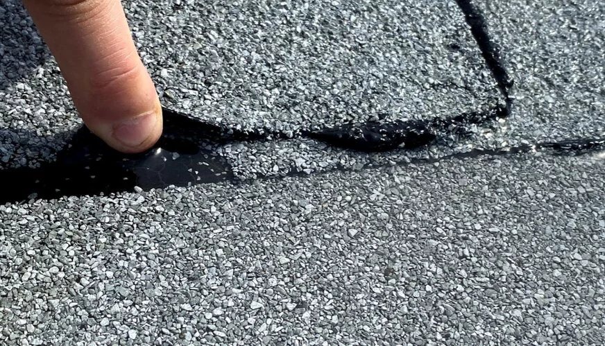 a finger inspecting a common roof damage in Calgary