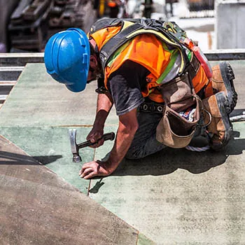 a roofer with hard-hat on, pouch and PFA harness