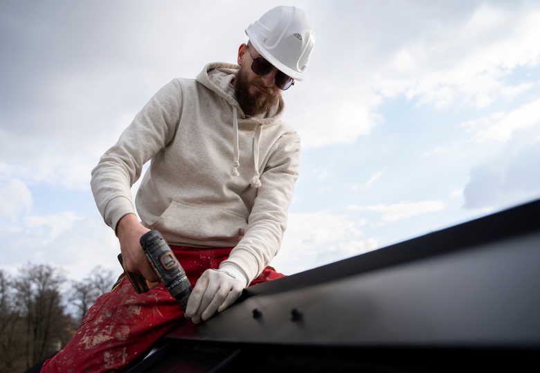 a roofer over a metal roof with a white hard hat